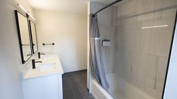 Un baño moderno con cabina de ducha de vidrio, un lavamanos blanco y un espejo.