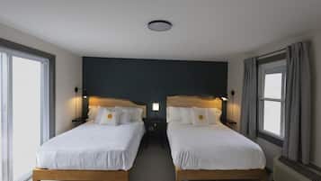 A double room with two beds, a dark accent wall, and a ceiling light.