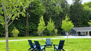 A grassy outdoor area with four blue Adirondack chairs arranged in a circle. - East Rock Inn (Great Barrington)