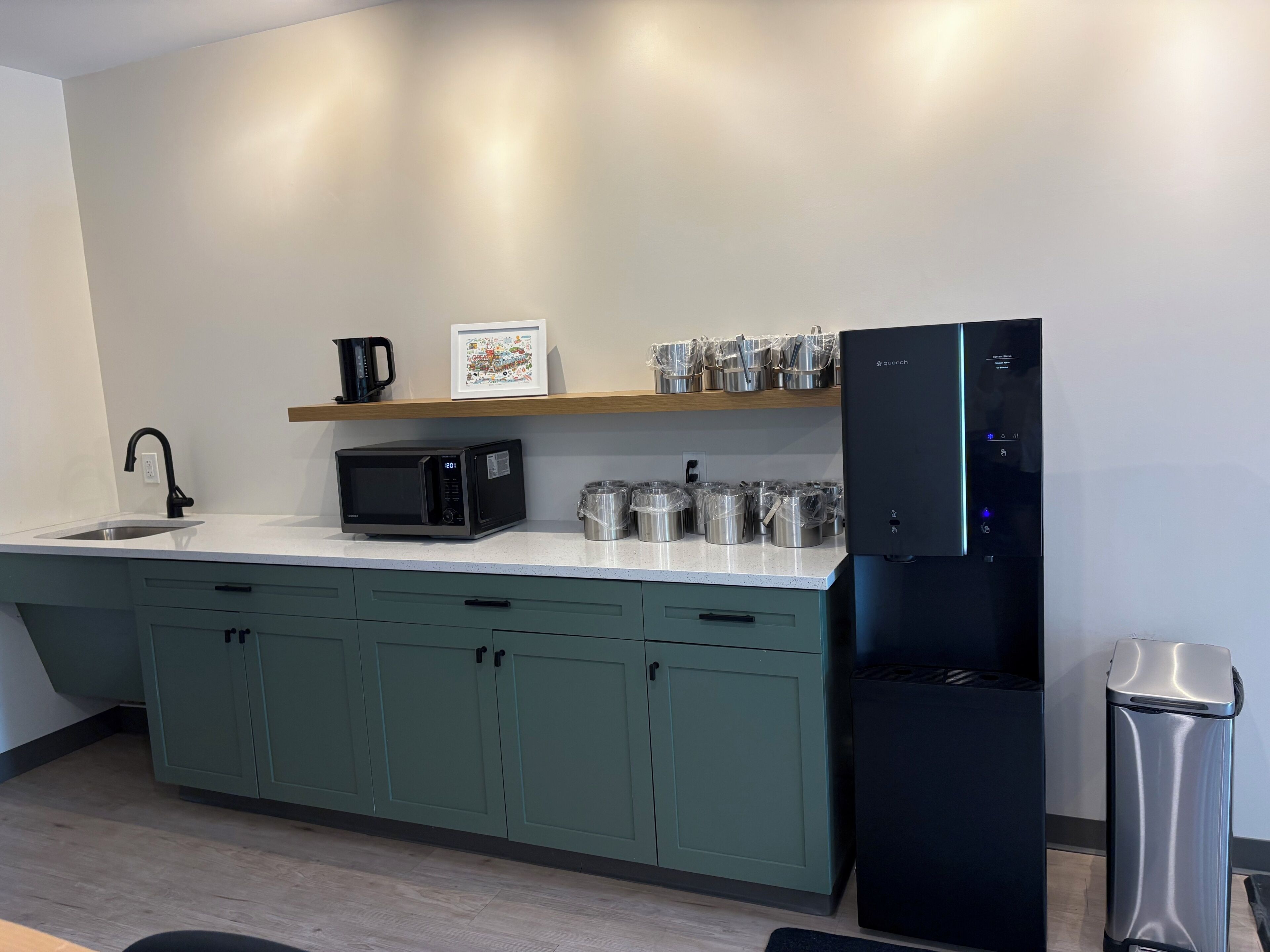 Una cocina moderna con un refrigerador negro, un microondas, un lavaplatos y gabinetes verdes.