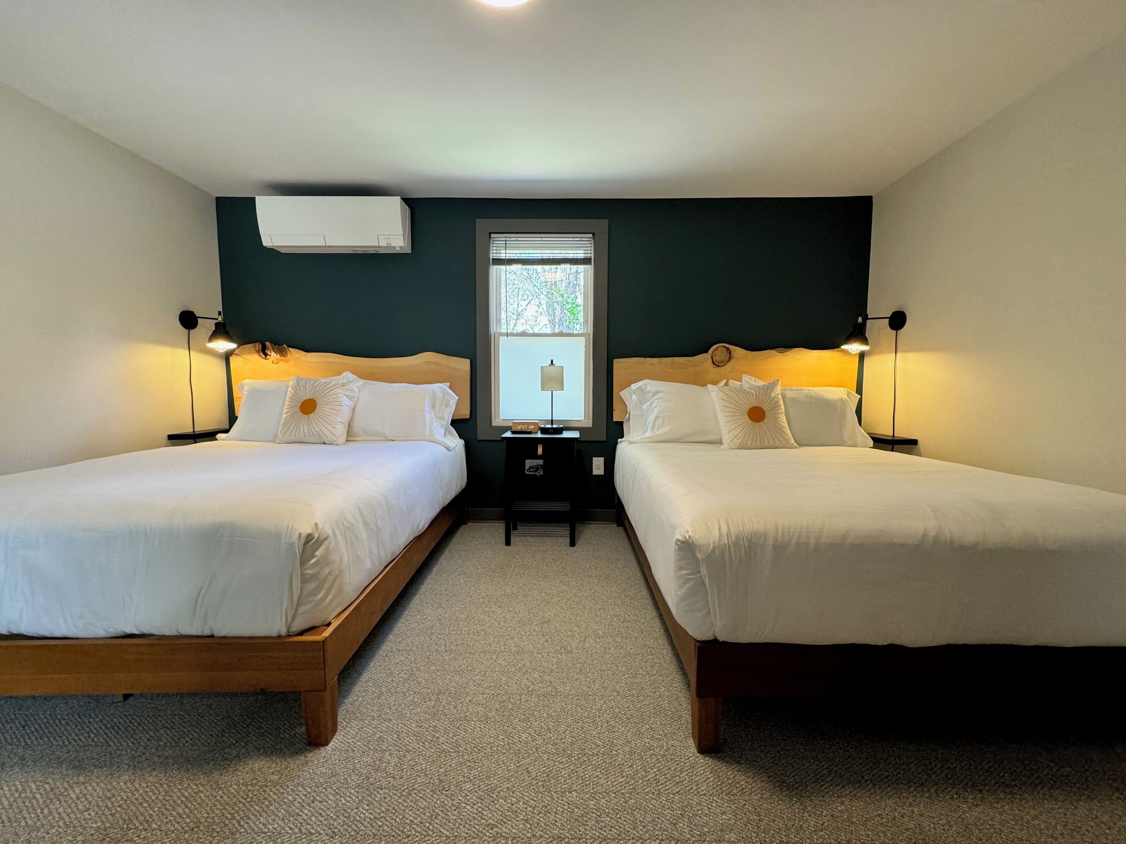 Ein Zimmer mit zwei Einzelbetten, einem kleinen Tisch und zwei Nachttischlampen.