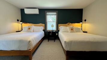 Ein Zimmer mit zwei Einzelbetten, einem kleinen Tisch und zwei Nachttischlampen.
