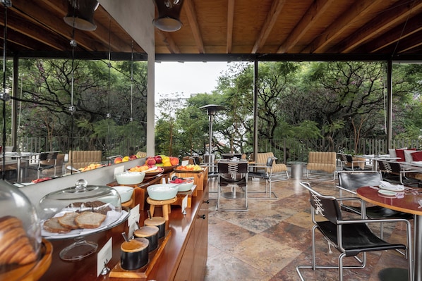 An outdoor dining area with a buffet setup, including various food items and seating arrangements. - Hotel Dama (Mexico City)