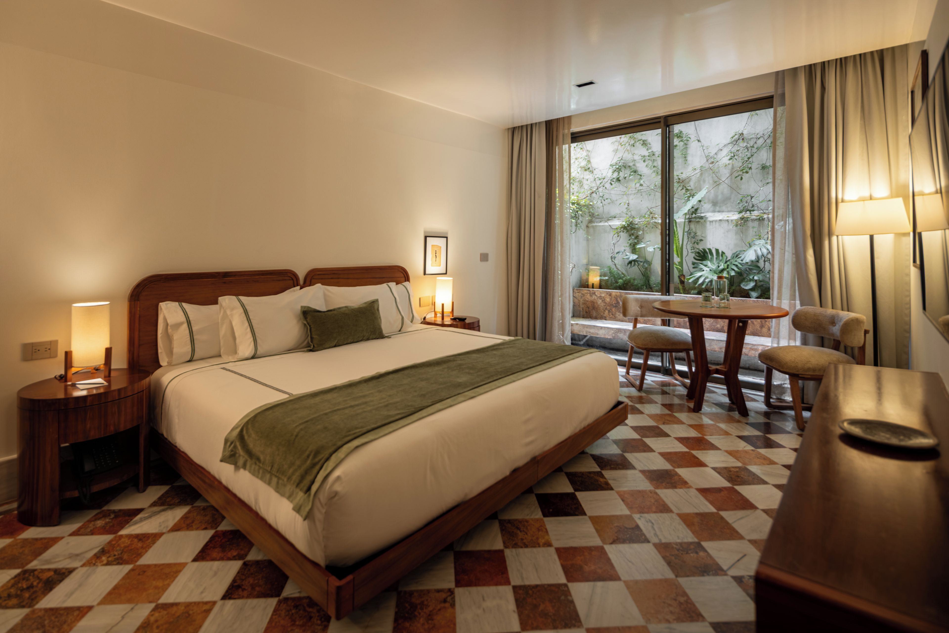 A hotel room with a large bed, a desk, a chair, and a window with curtains.
