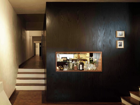 A hallway with a dark wooden wall, a framed mirror, and a staircase. - Hotel Dama (Mexico City)