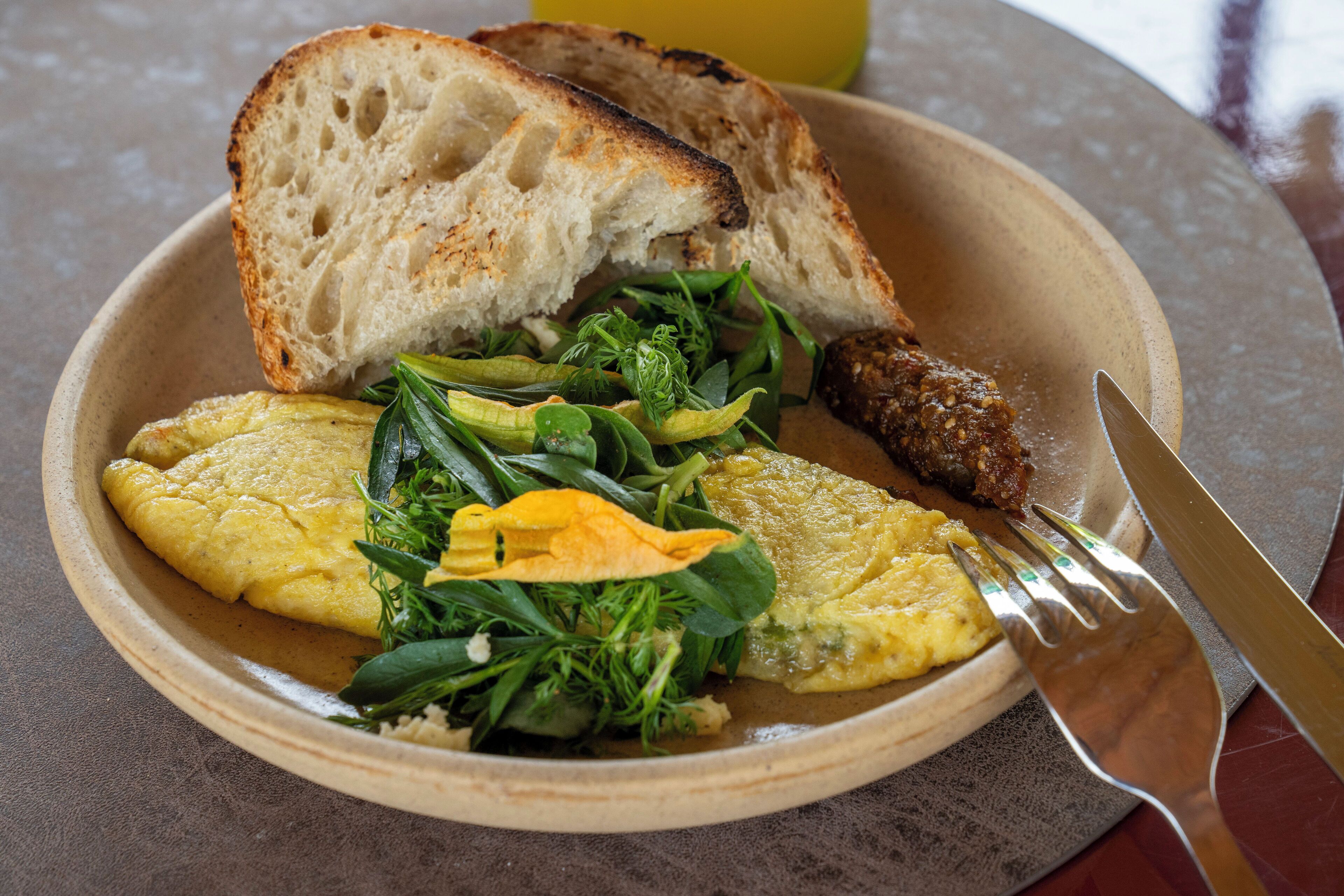 Un plato con huevos revueltos, vegetales verdes y una rebanada de tostada.