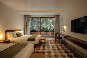 A hotel room with a bed, a desk, a chair, a television, and a view of greenery outside. - Hotel Dama (Mexico City)