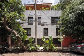 A multi-story building with a balcony, surrounded by trees and a parked car. - Hotel Dama (Mexico City)