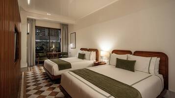 A hotel room with two beds, a checkered floor, a wooden headboard, a nightstand, a lamp, and a view of the outdoors.