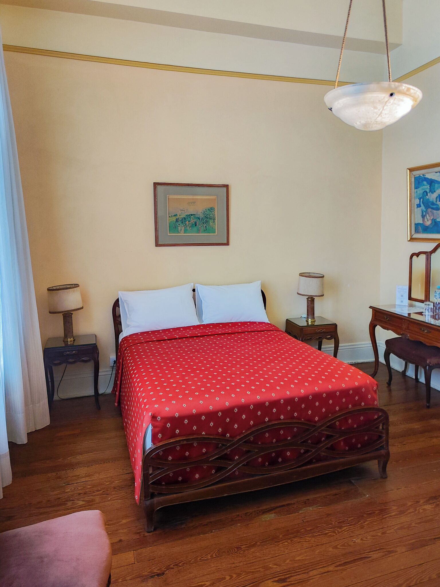 A neatly arranged bedroom with a bed, bedside tables, a desk, and a chair.