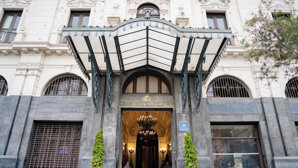 The entrance of Gran Hotel Bolívar with a classic architectural design, featuring a grand entrance, a chandelier, and a flag. - GRAN HOTEL BOLIVAR (Lima)