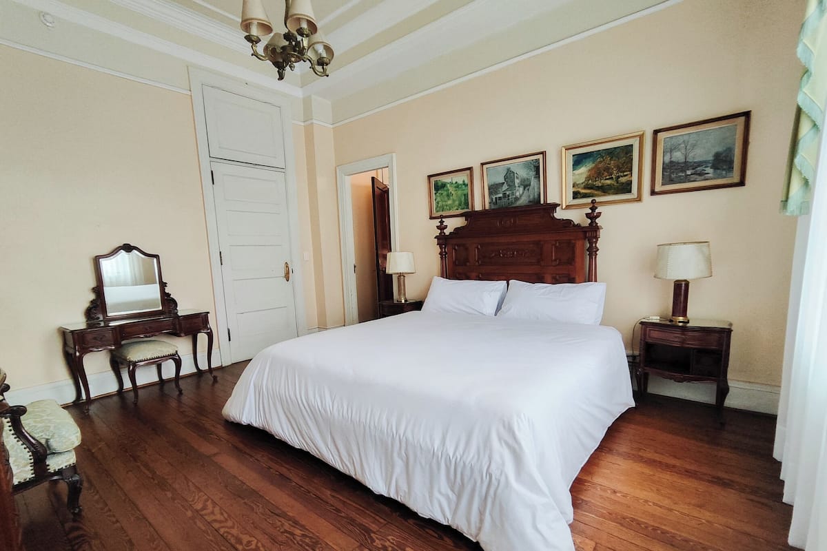 Un dormitorio con una cama grande, un aparador de madera, un espejo y una puerta.