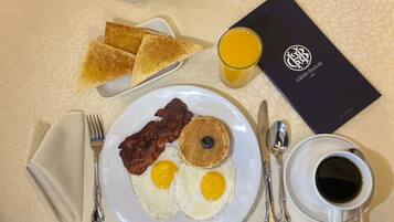 A breakfast plate with eggs, bacon, and a blueberry, toast, a glass of orange juice, and a menu.