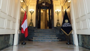 A grand hallway with a high ceiling, a chandelier, and a staircase leading to an entrance. - GRAN HOTEL BOLIVAR (Lima)