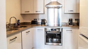 A modern kitchen with stainless steel appliances, white cabinetry, and a built-in oven. - Aspire City Centre Suite - PingPong & Netflix (West Midlands)