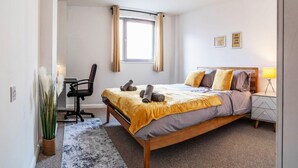 A bedroom with a bed, a desk, a chair, a lamp, and a window with curtains. - Aspire City Centre Suite - PingPong & Netflix (West Midlands)