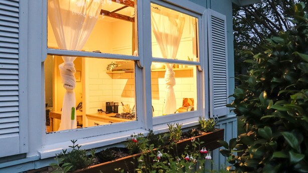 A kitchen with white cabinets, a stove, and a window with white curtains.