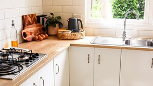 A kitchen with white cabinets, a gas stove, a sink, and a window with greenery outside.