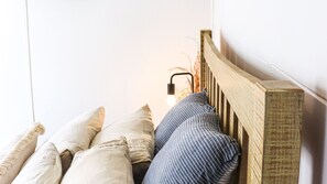 Un lit avec une tête de lit en bois, plusieurs oreillers et une lampe de chevet.