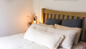 A bed with a wooden headboard, two pillows, and a bedside lamp.