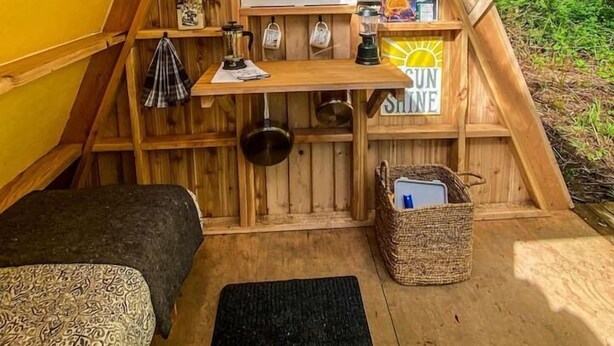 A cozy attic-style room with wooden beams, a window, and a small kitchenette.