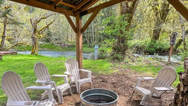 An outdoor seating area with Adirondack chairs and a fire pit. - Waterfront Getaway w/ Sauna and BBQ (Longview)