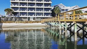 A beachfront hotel with multiple balconies, a wooden pier, and a sandy beach. - Harbor Inn (Wrightsville Beach)