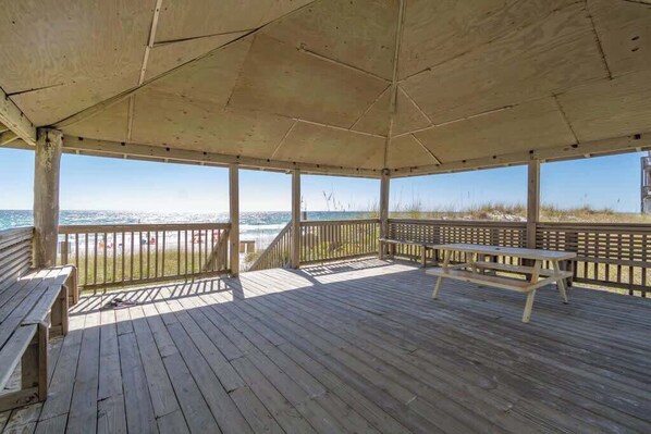A wooden deck with a picnic table and benches overlooking the beach.