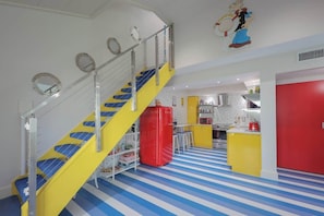 A brightly colored interior with a yellow staircase, a red refrigerator, and a kitchen area. - Sea Cabins 4C - Beach! Pool! Free Beach Service! (Miramar Beach)