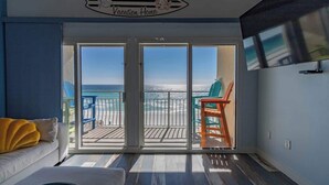 Et værelse med balkon med udsigt over stranden, et skilt med teksten "Aronas de Crystal Vacation Home" og et fjernsyn monteret på væggen.