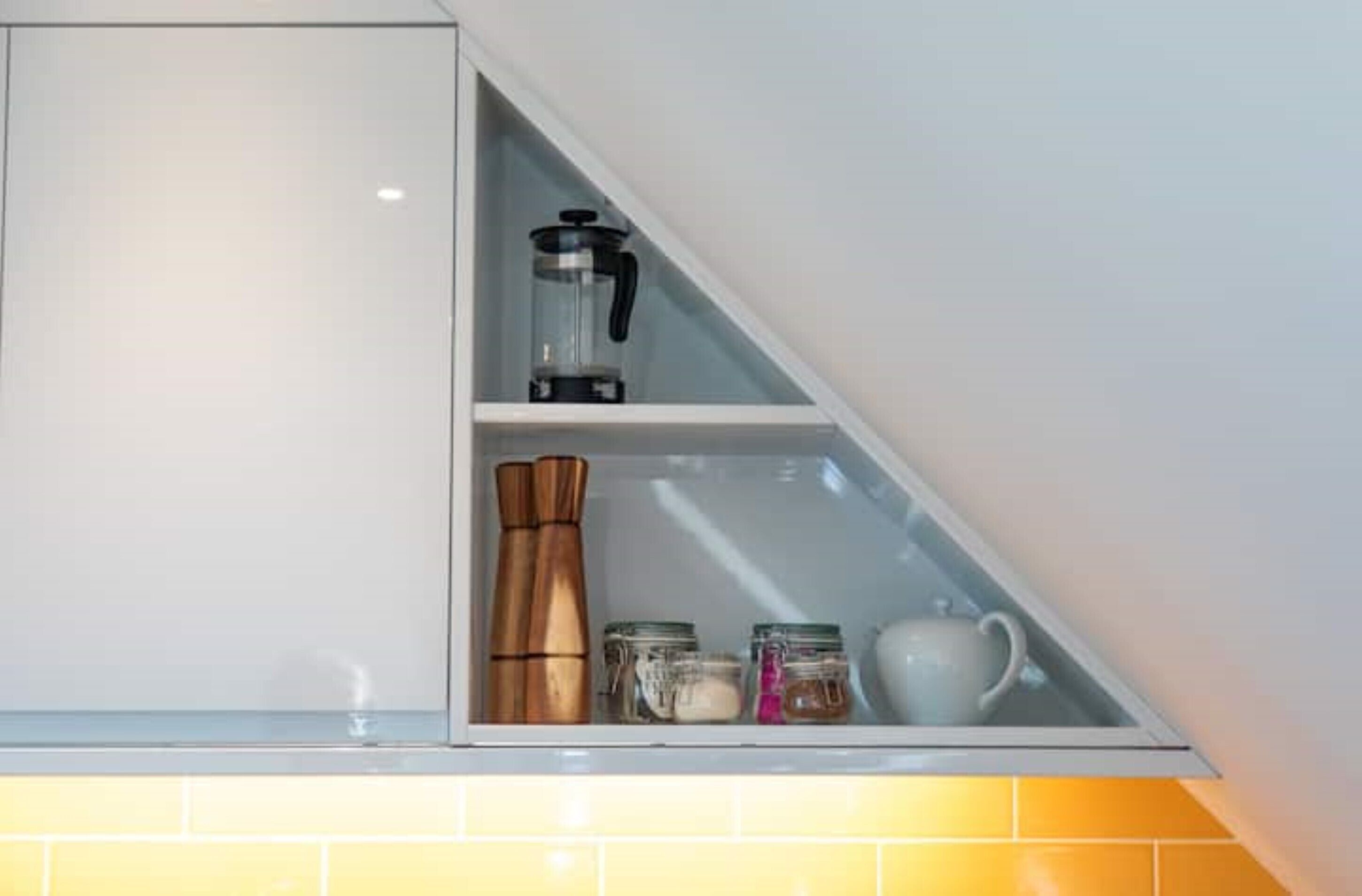 A kitchen with a built-in coffee maker, spice rack, and storage jars.