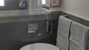 A modern bathroom with a white sink, dark marble countertop, and a towel rack with two towels. - Studio apartment on Plebiscito Street with kitchenette and balcony on the courtyard (Catania)