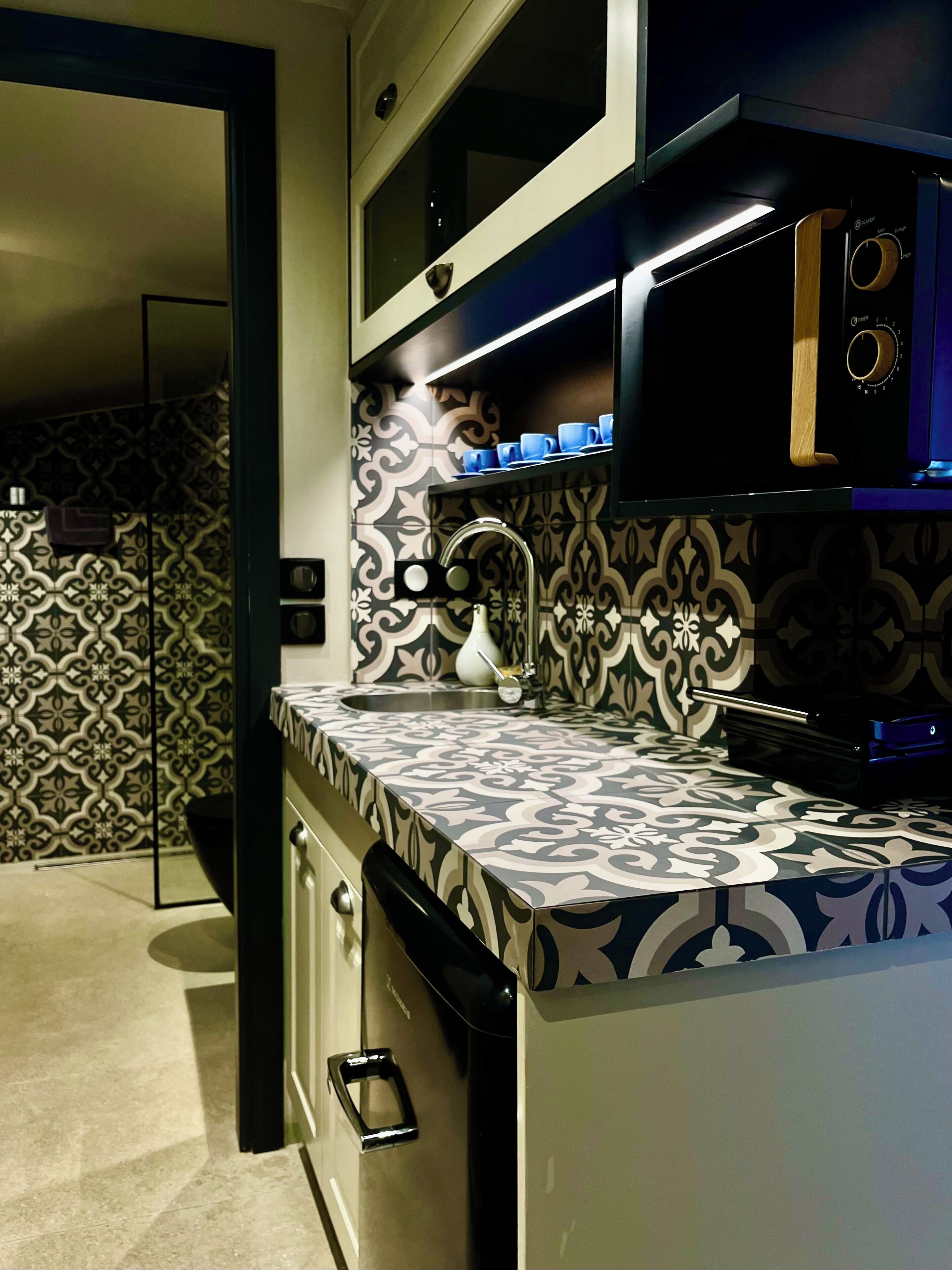 A modern kitchen with patterned backsplash, stainless steel appliances, and a built-in microwave.