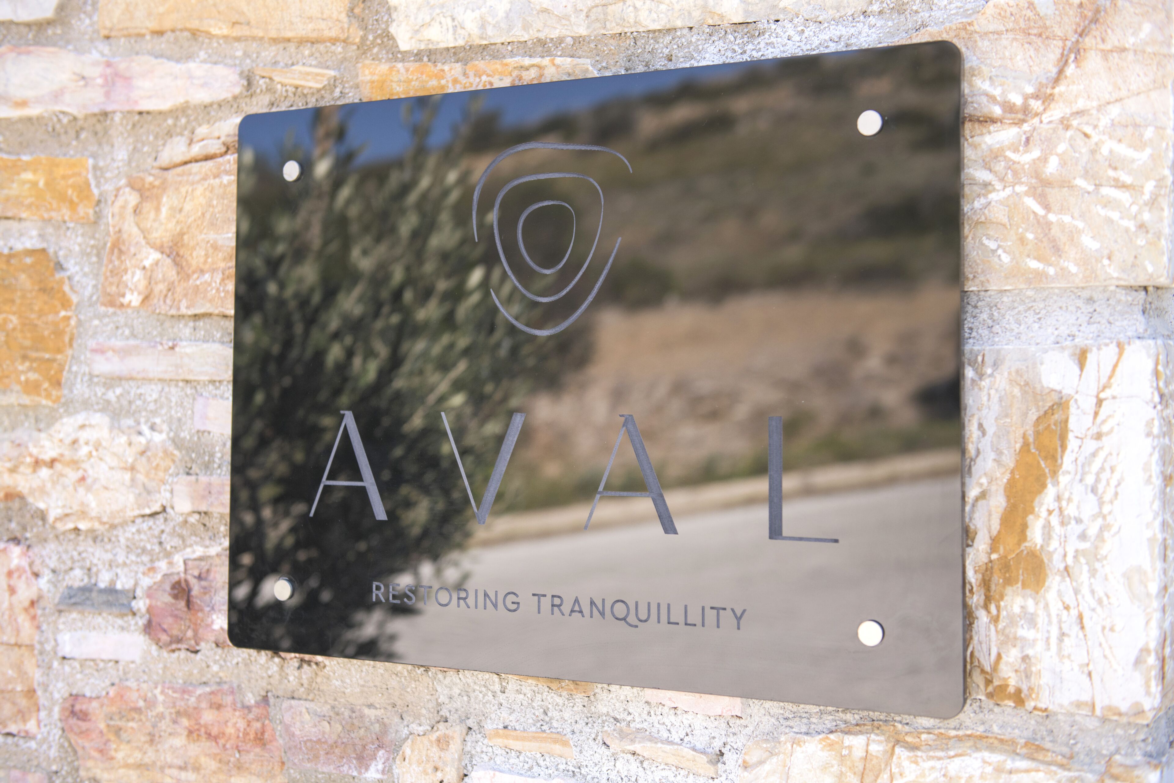 A metal plaque with the text "AVAL RESTORING TRANQUILLITY" mounted on a stone wall.