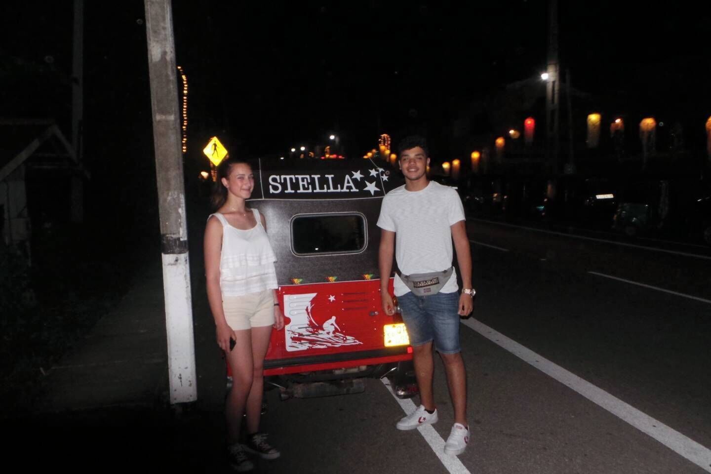 Two people standing next to a bus with 'STELLA' written on it.