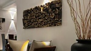 A modern living room with a sofa, a decorative wall piece, and a vase with branches. - Villa Luxury Virginia With Pool and Garden (Gonapinuwala)