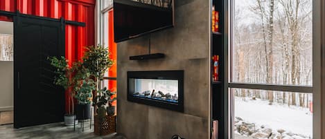 A modern interior with a fireplace, large windows, and a red accent wall.
