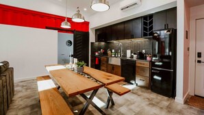 A modern kitchen with a wooden table, black cabinets, and a black refrigerator. - The Buckeye Box - The James (McArthur)