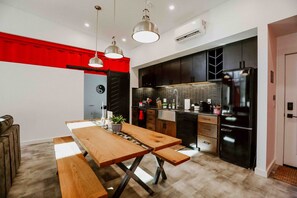 A modern kitchen with a wooden table, black cabinets, and a black refrigerator. - The Buckeye Box - The James (McArthur)