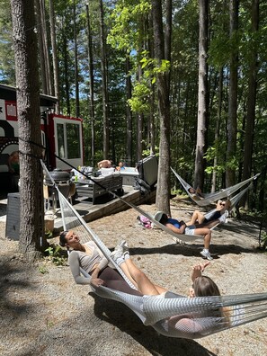 A campsite with hammocks, a fire truck, and a portable grill.