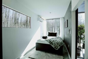 A modern bedroom with a large window, a bed, and a small bedside table. - The Buckeye Box - The James (McArthur)