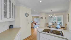 A modern kitchen with white cabinets, a built-in stove, and a dining area with a chandelier. - 43 Fairway Dunes by Avantstay Coastal Charm + Golf! (Isle of Palms)