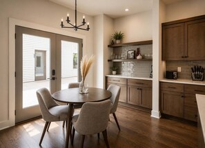 Une cuisine moderne avec des meubles en bois, une table de salle à manger ronde entourée de chaises et un lustre.