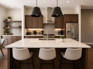 Une cuisine moderne dotée d’un grand îlot central, de tabourets de bar et d’appareils électroménagers en acier inoxydable.