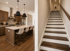 Une cuisine moderne dotée d’un îlot central, de tabourets de bar et de luminaires suspendus.
