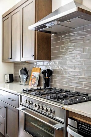 A modern kitchen with stainless steel appliances, wooden cabinets, and a tiled backsplash. - 2 West End Homes with Stunning Rooftop Views (Nashville)