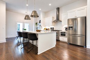 Una cocina moderna con una isla central, electrodomésticos de acero inoxidable e iluminación colgante.