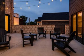 Eine Terrasse im Freien mit Ziegelwänden, Holzmöbeln und Lichterketten.