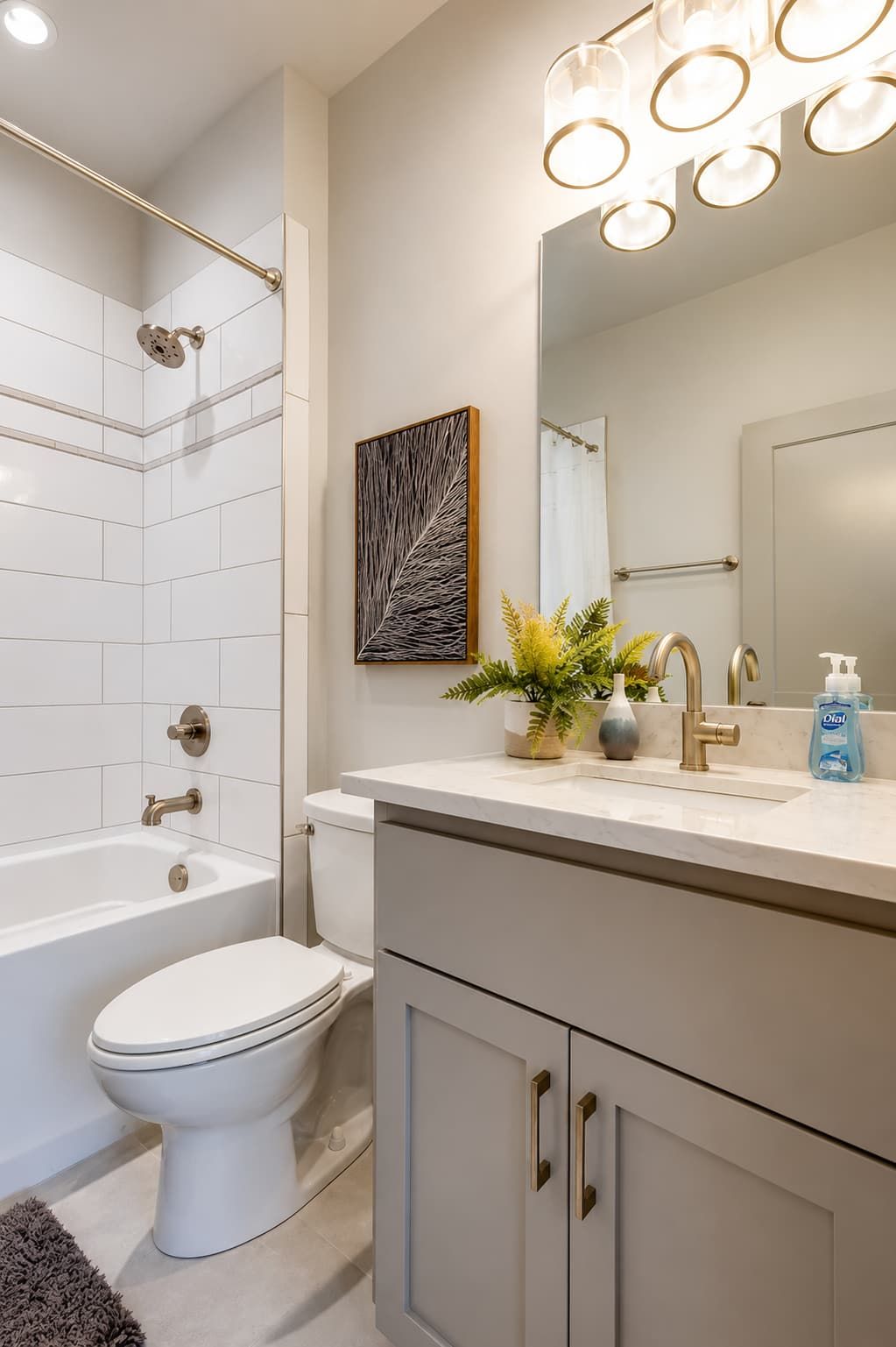 A modern bathroom with a white bathtub, toilet, and vanity with a mirror and sink.