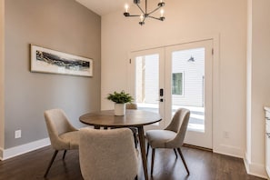 Un coin repas avec une table ronde, quatre chaises, une plante en pot et un lustre.